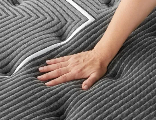 Person's hand touching Beautyrest mattress to feel its softness